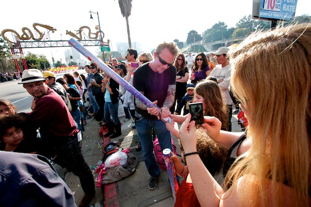 A man helps a young girl fire her cardboard canon as the parade goes by.