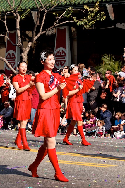 Women in red dresses perform a fan dance as they march in the 2011 Golden Dragon Chinese New Year Parade.