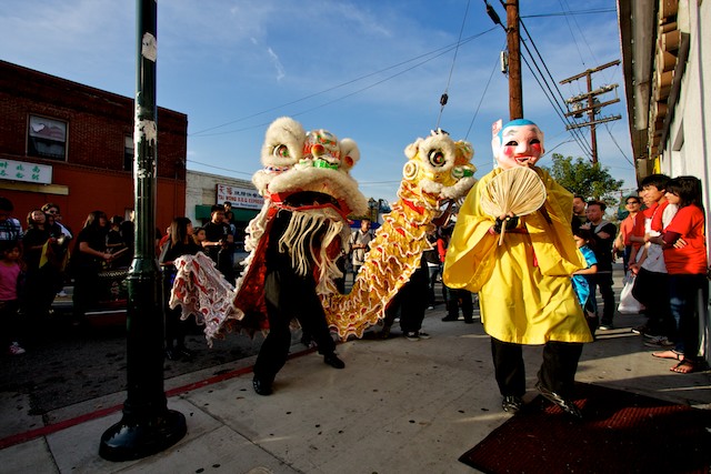 The big head buddha and two lions dance in front of a restaurant in Chinatown.