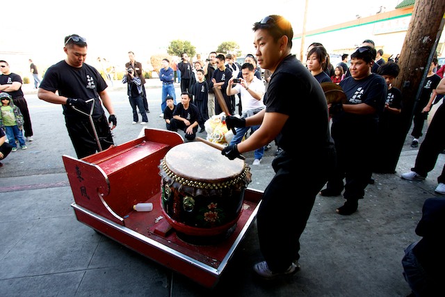 A man from the East Wind troupe plays the drum outside of a restaurant in Chinatown.